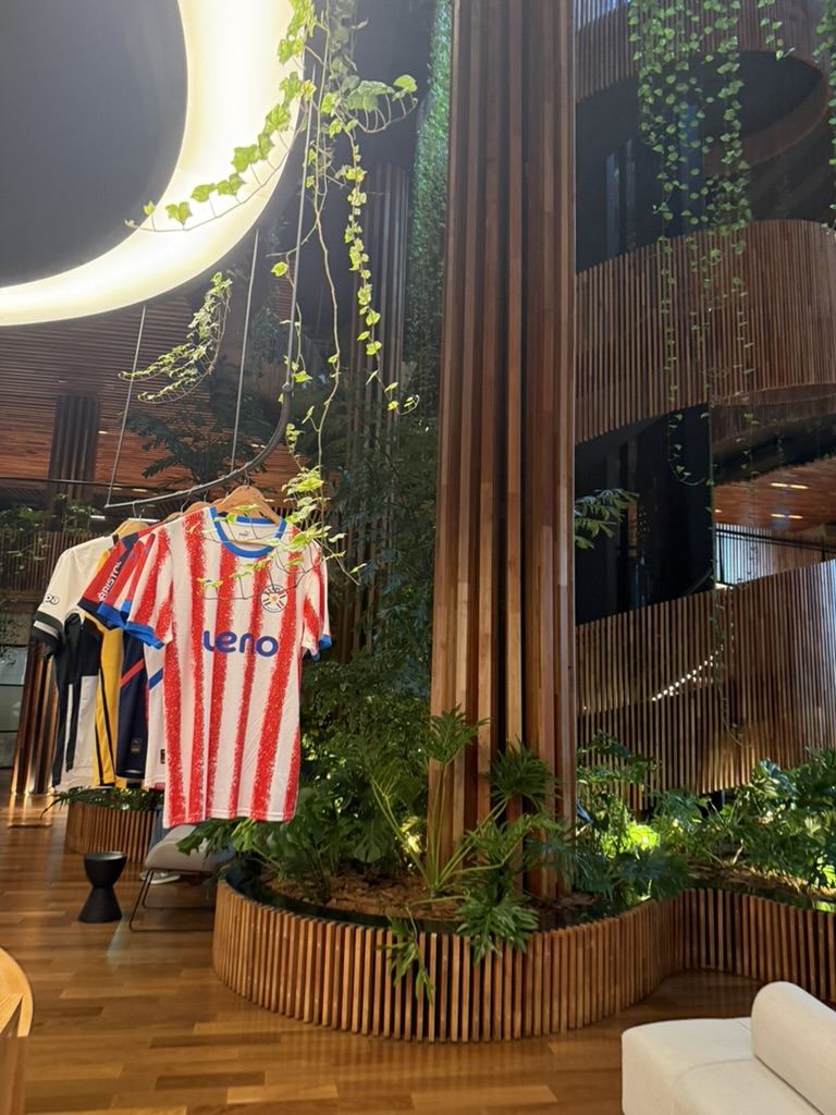 Interior de shopping com plantas e camisas listradas vermelhas e brancas expostas